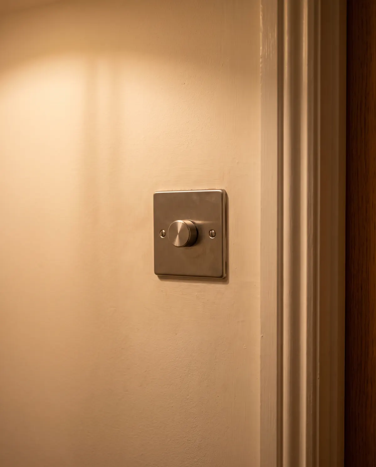 Brushed steel dimmer switch beside a door frame