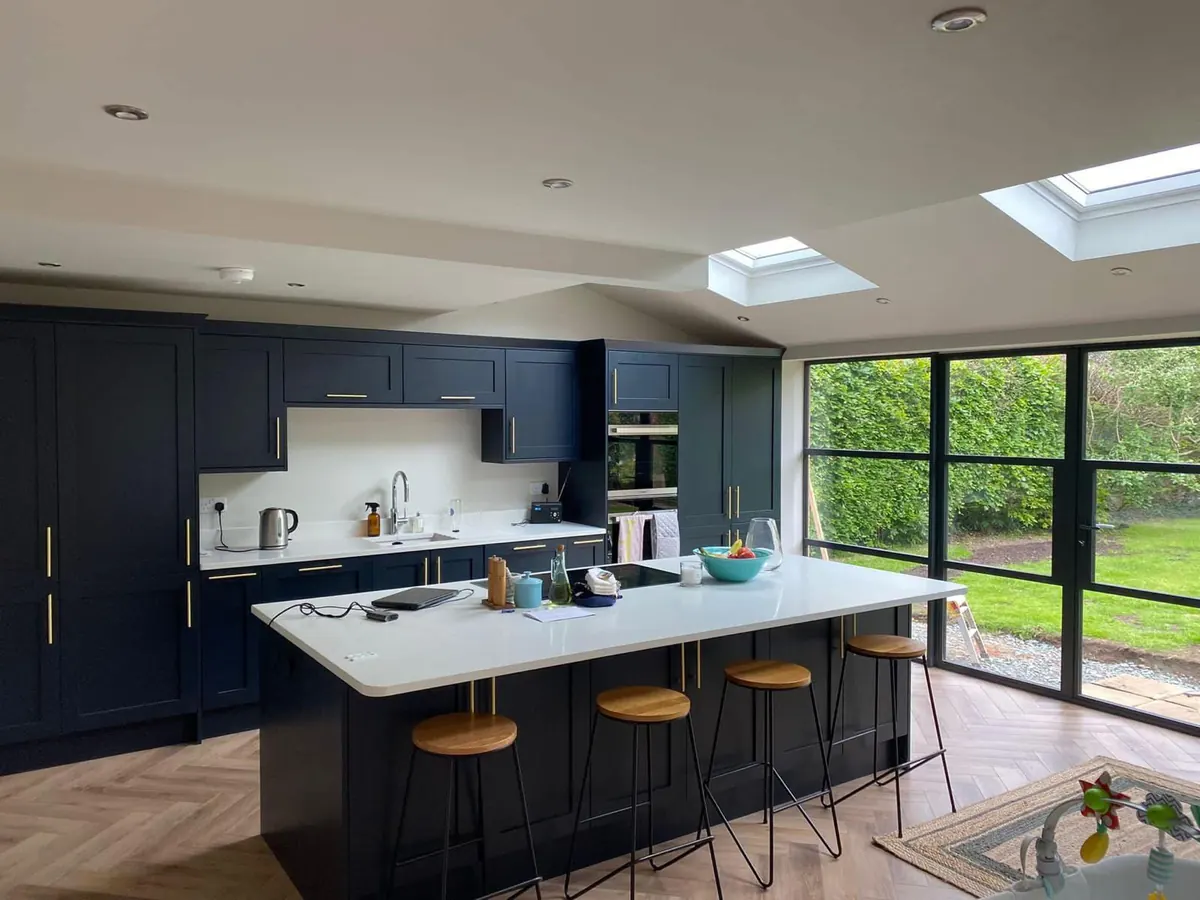 Navy kitchen island lit by three pendants under roof lanterns